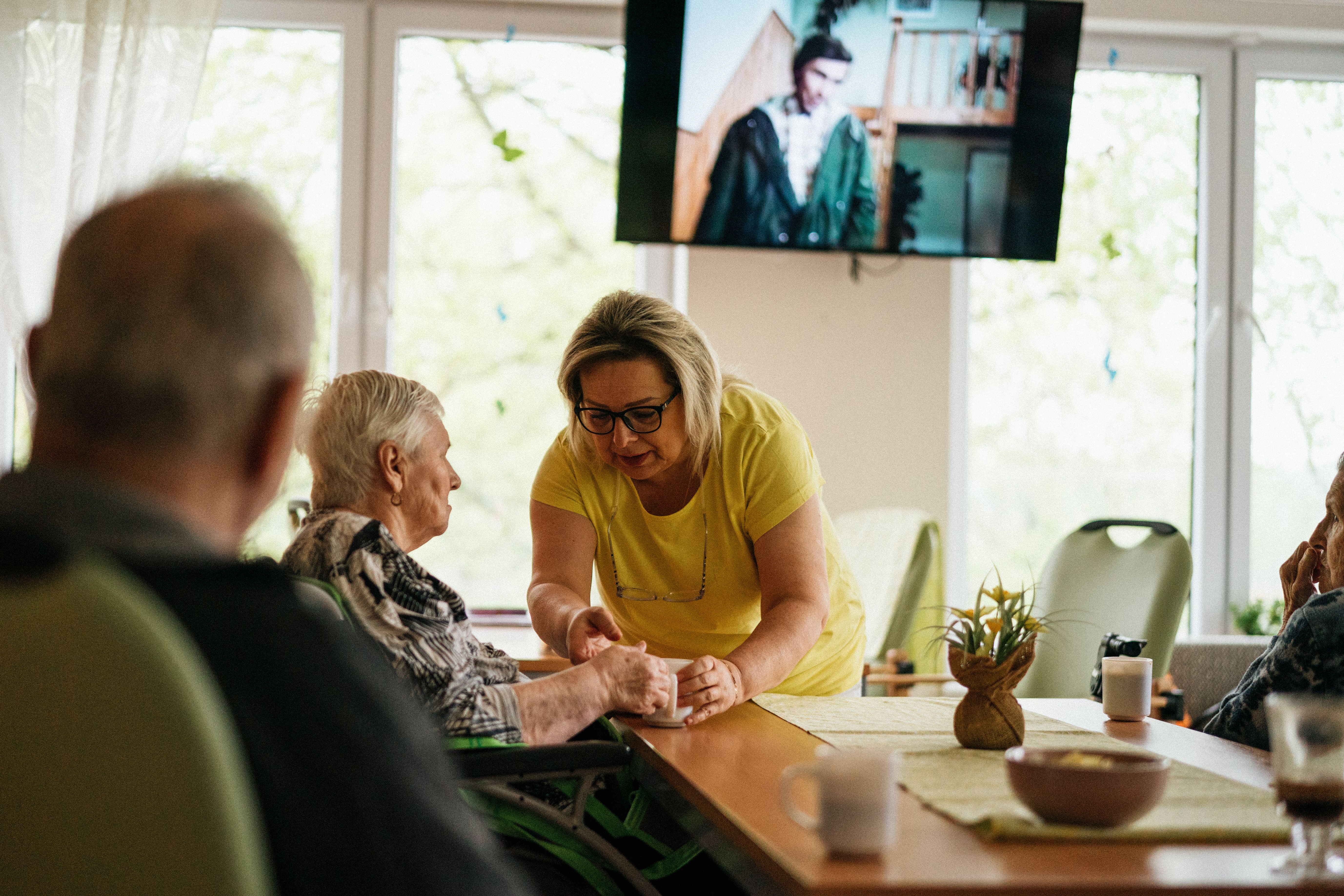 Caregiver sharing a warm moment with an elderly client at the dining table