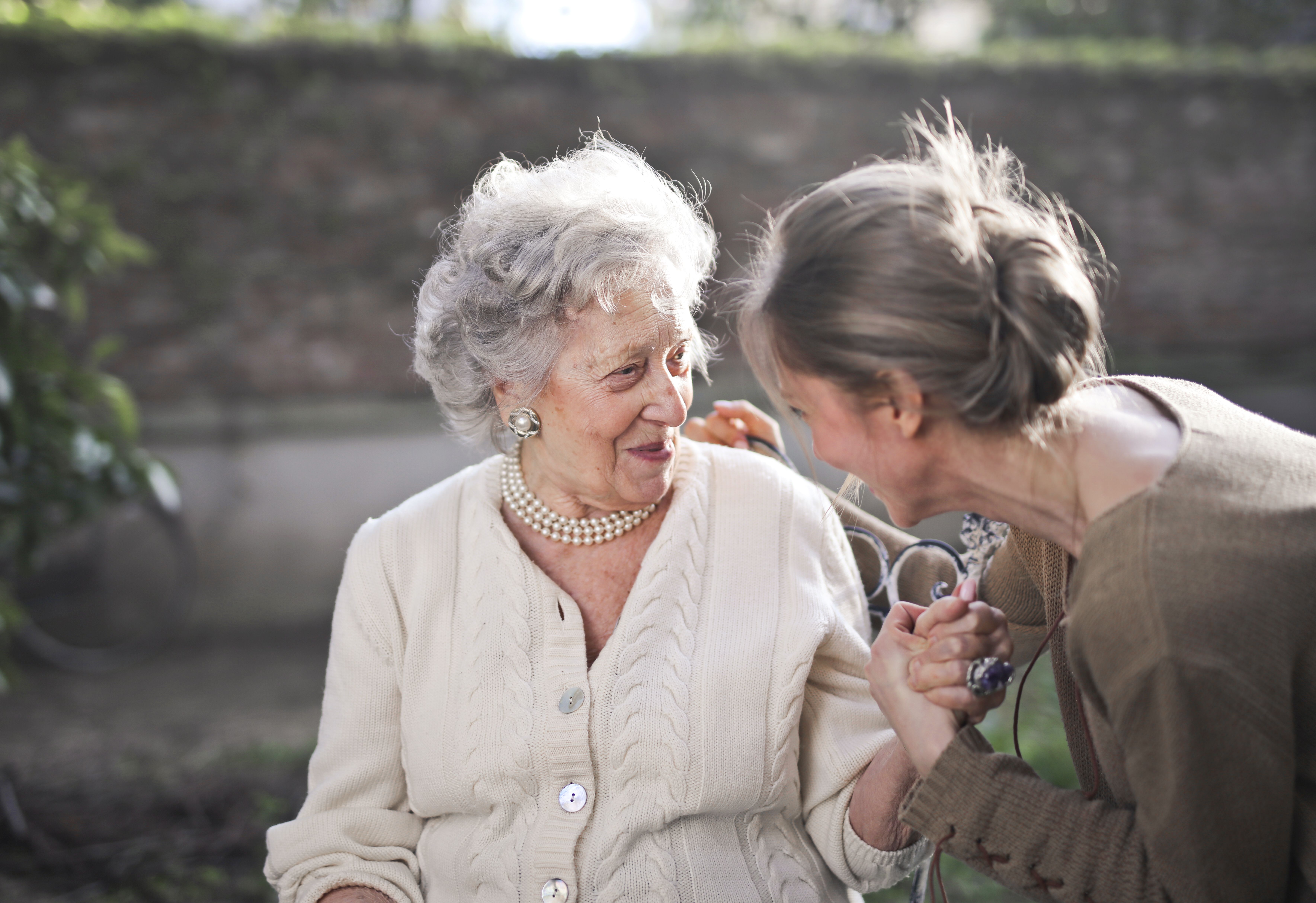 Caregiver sharing a warm, joyful moment with an elderly client outdoors
