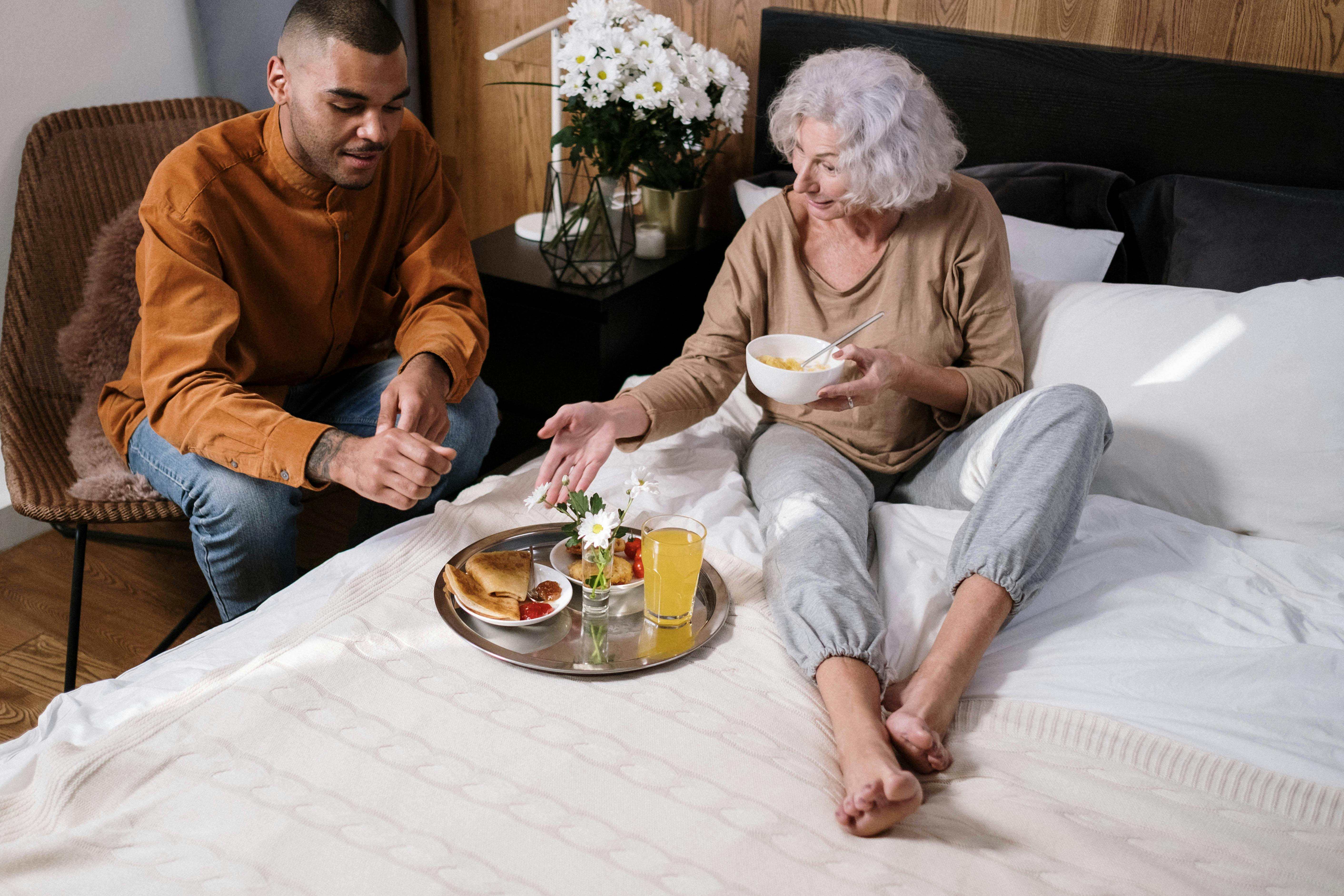 Caregiver bringing a meal to an elderly woman at home